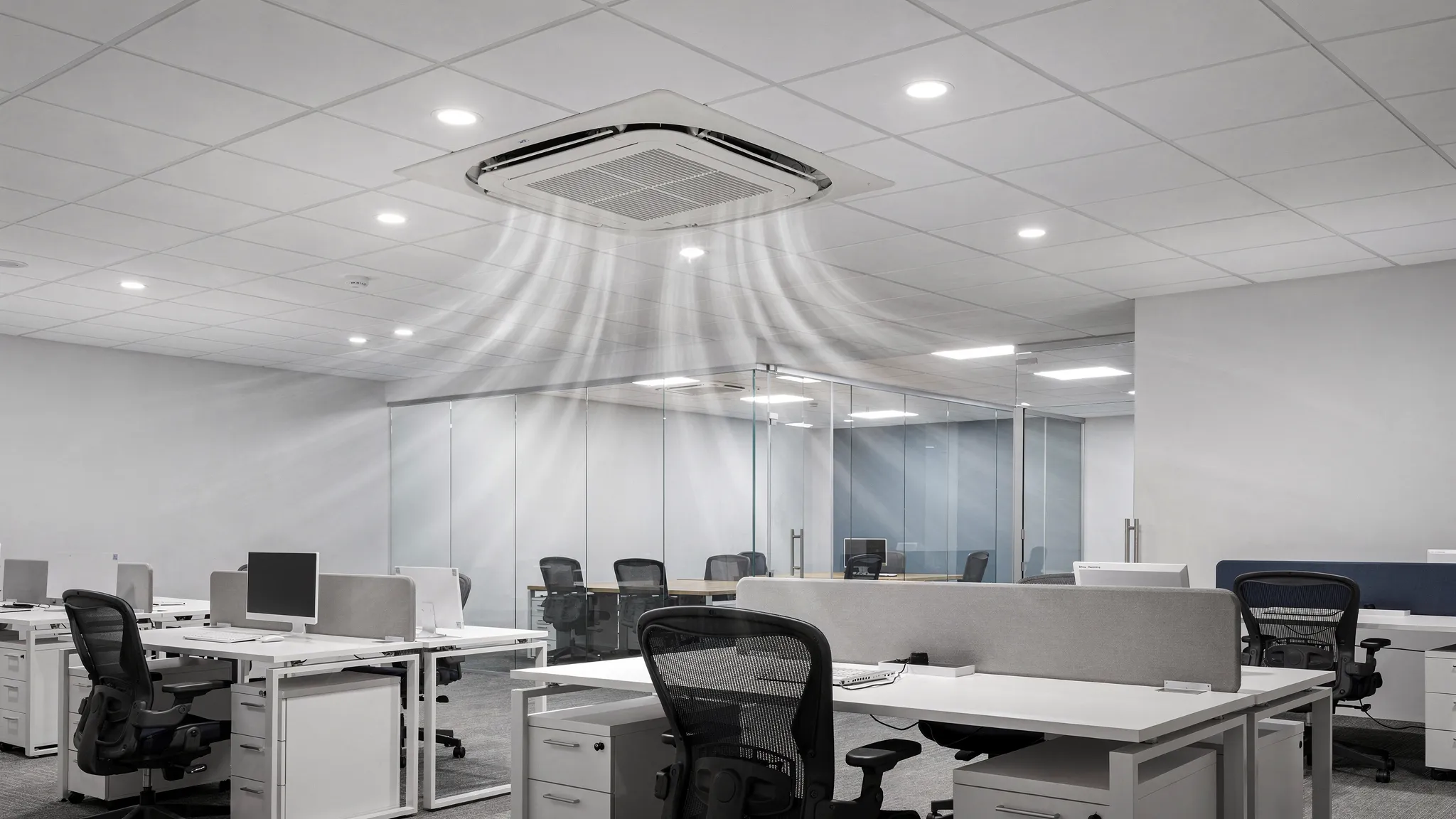 Ceiling cassette air conditioner installed in a modern commercial office with a false ceiling grid, recessed lights and evenly distributed airflow across desks and meeting area.